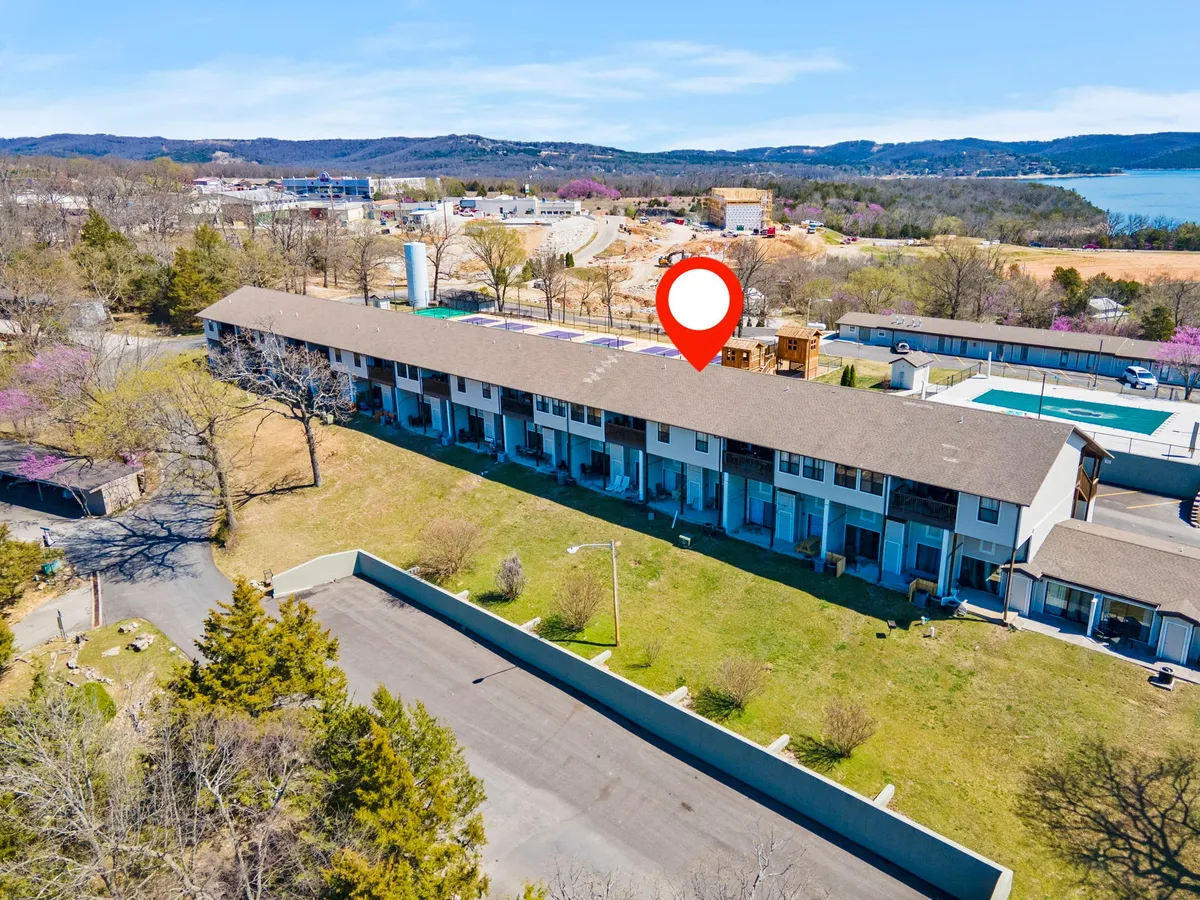 This image displays the building's exterior, highlighting the pool area and surrounding landscaped grounds. The setting is bright and welcoming, with guests enjoying sunny weather near the water. The view also hints at the proximity to local attractions and amenities.