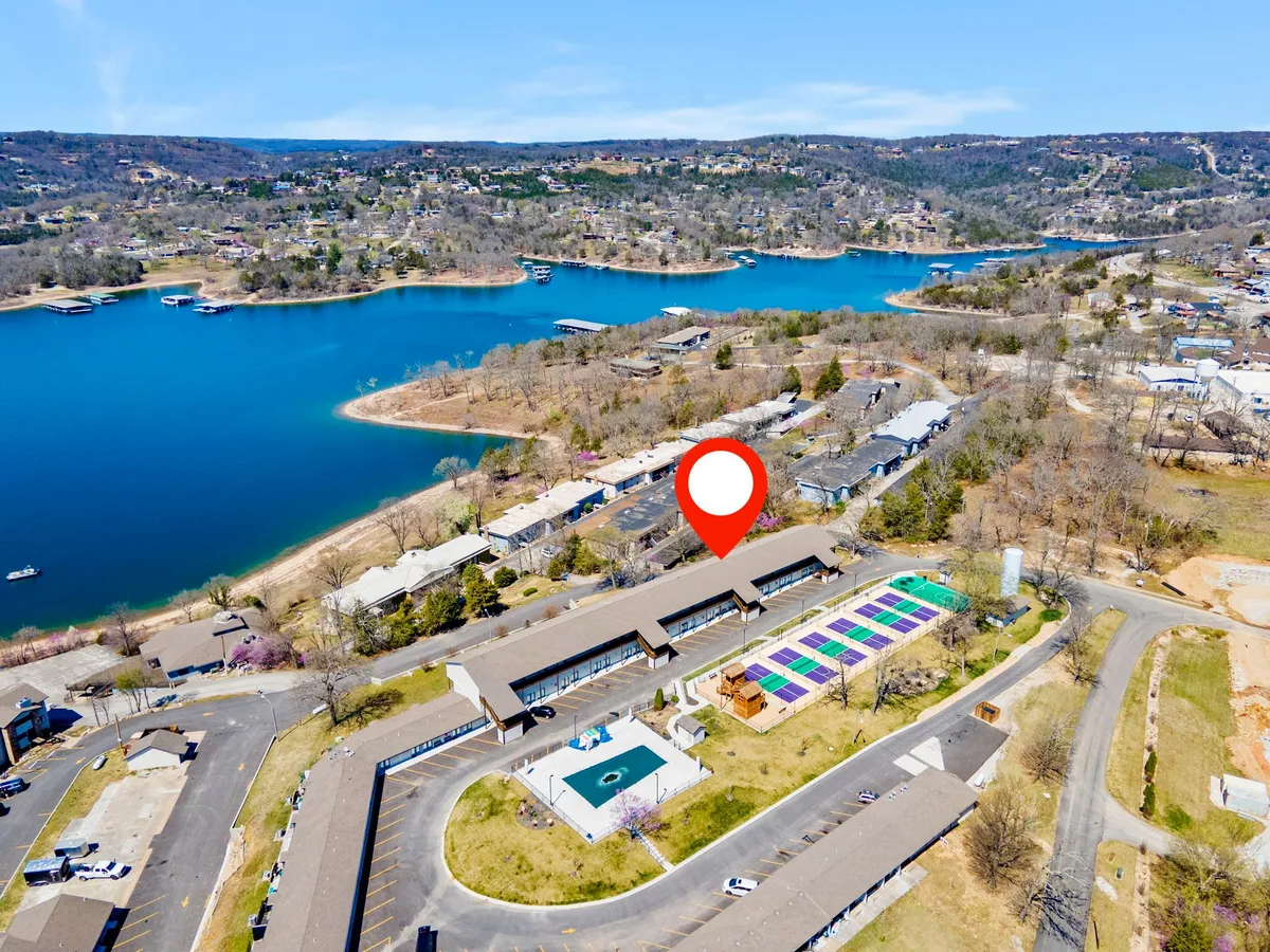 A lively outdoor area featuring a swimming pool, colorful patio spaces, views of the lake, and a scenic landscape. The space is inviting for swimming, boating, relaxing by the pool, and gathering for summer barbecues or picnics.
