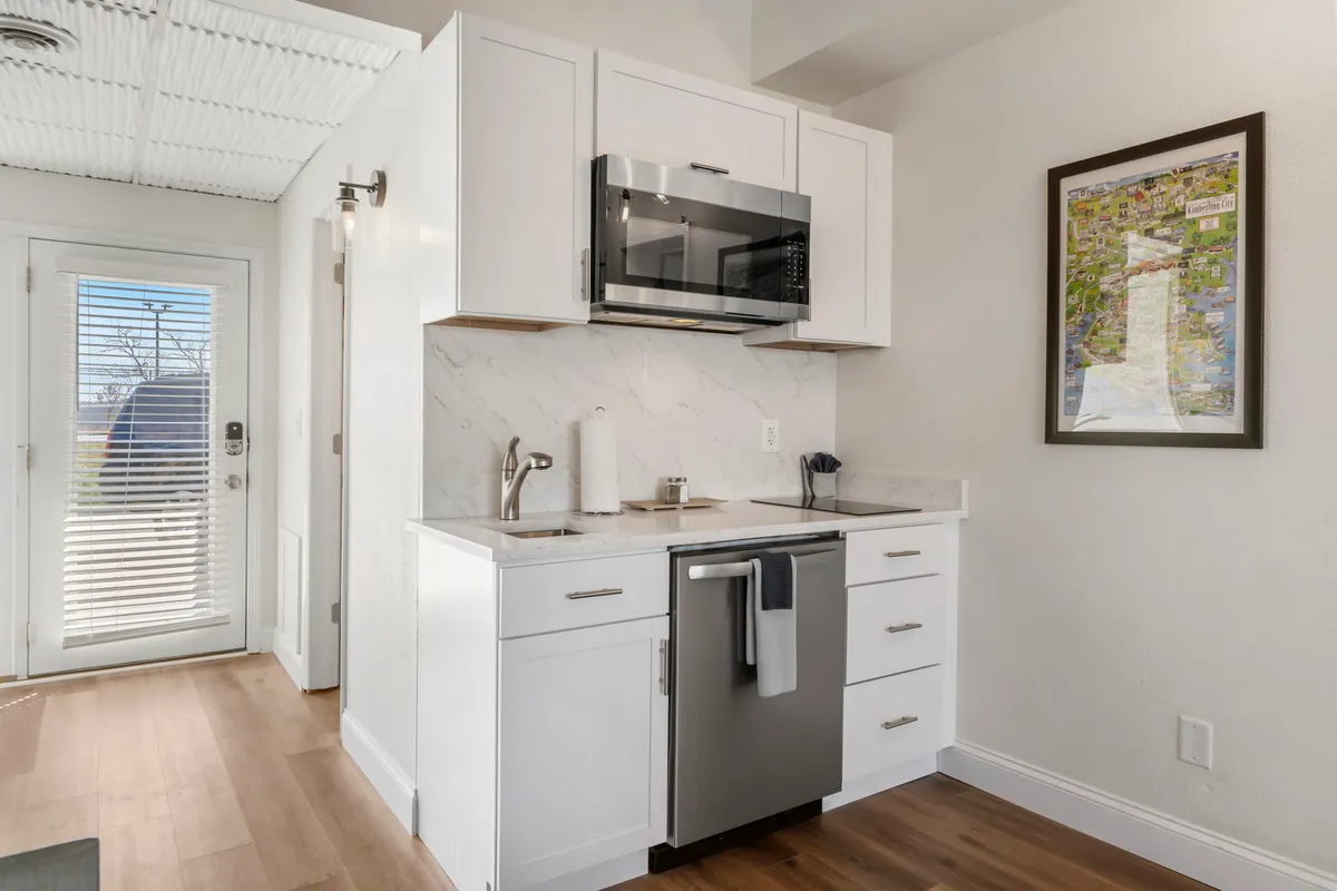 A modern and cozy kitchenette featuring essential appliances, generous counter space, and a framed map on the wall. The layout invites both cooking and socializing, with an atmosphere that suggests memorable meal prep and intimate gatherings.