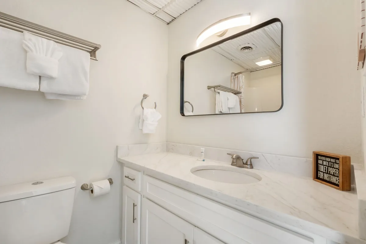 A modern bathroom with a vanity, large mirror, neatly arranged towels, and tasteful décor. The space is fresh, bright, and clearly emphasizes convenience and self-care routines.