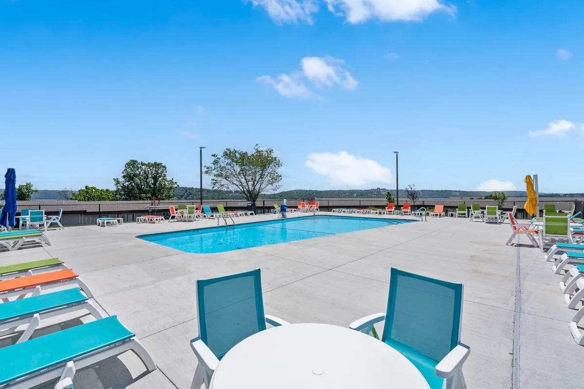 An outdoor swimming pool surrounded by lounge chairs and colorful umbrellas, with people swimming, sunbathing, and socializing. The scene is cheerful, vibrant, and epitomizes the lively resort atmosphere described in the section.